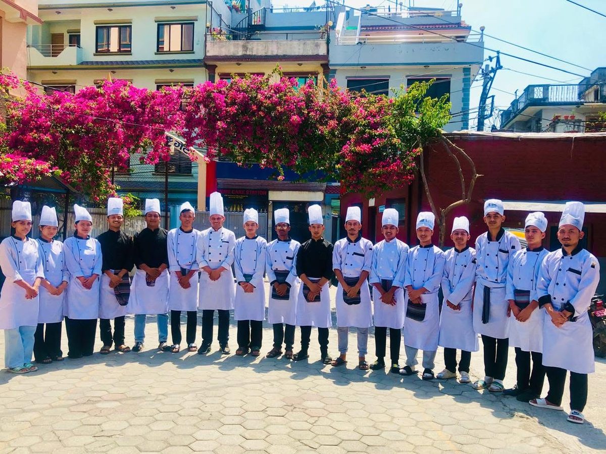 Precious culinary students in chef whites lined up outside the college gate