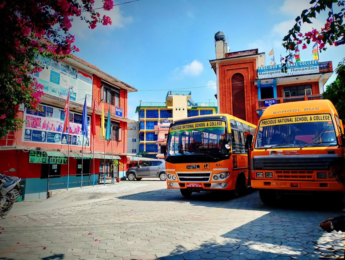 Precious National School & College campus with school buses at the entrance